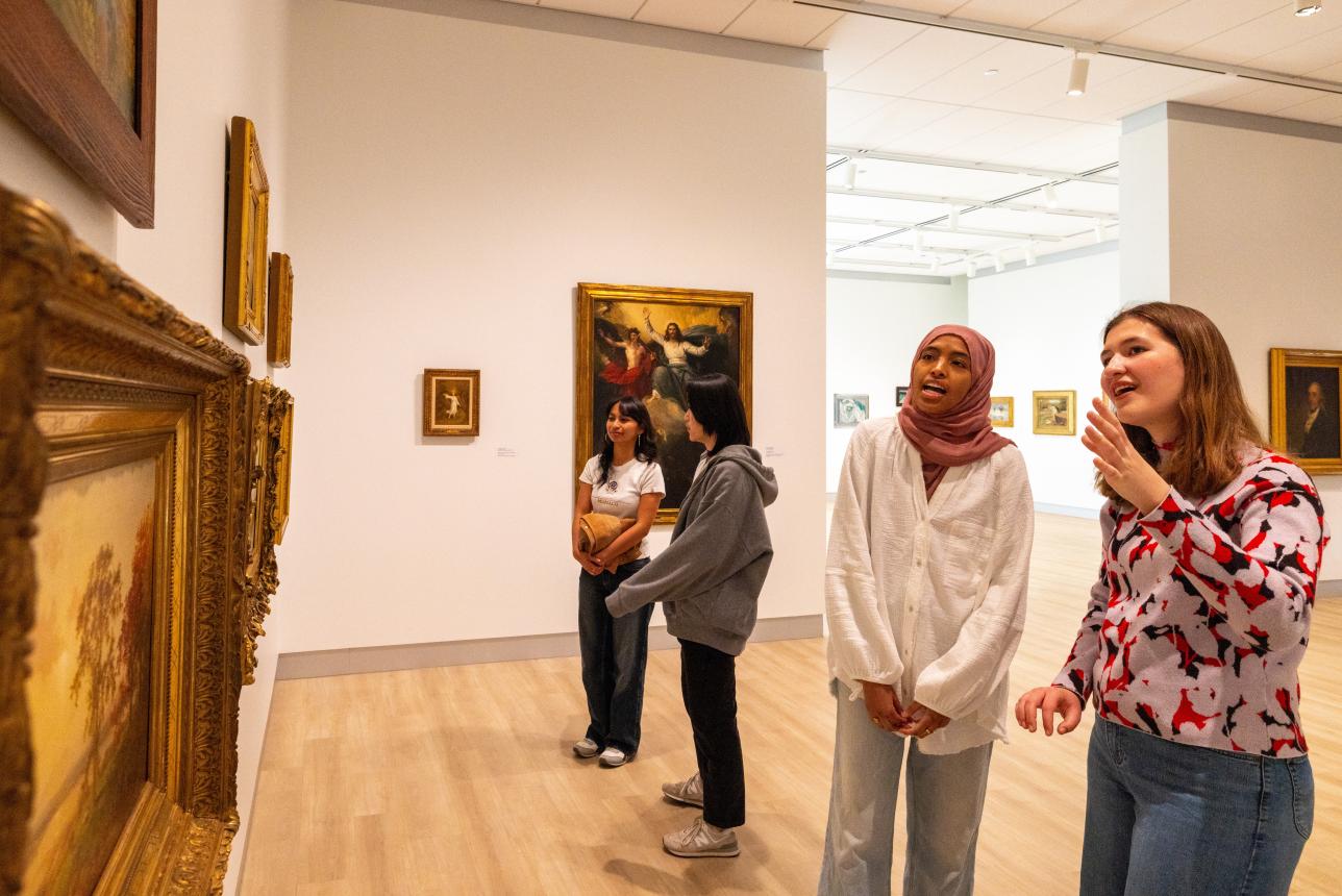 Four female students in art museum talking about paintings